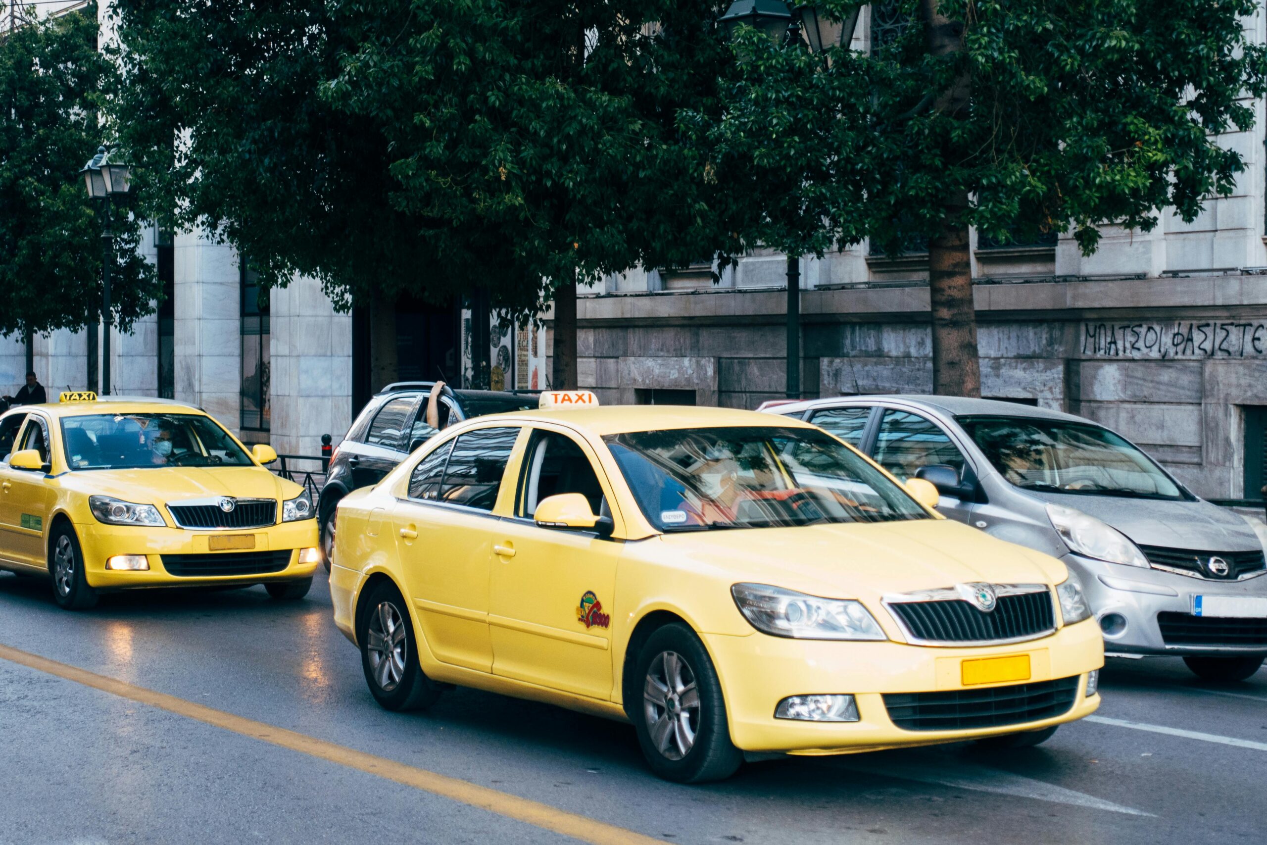 Yellow taxis lining the street in Athens, Greece, showcasing city's bustling transportation.
